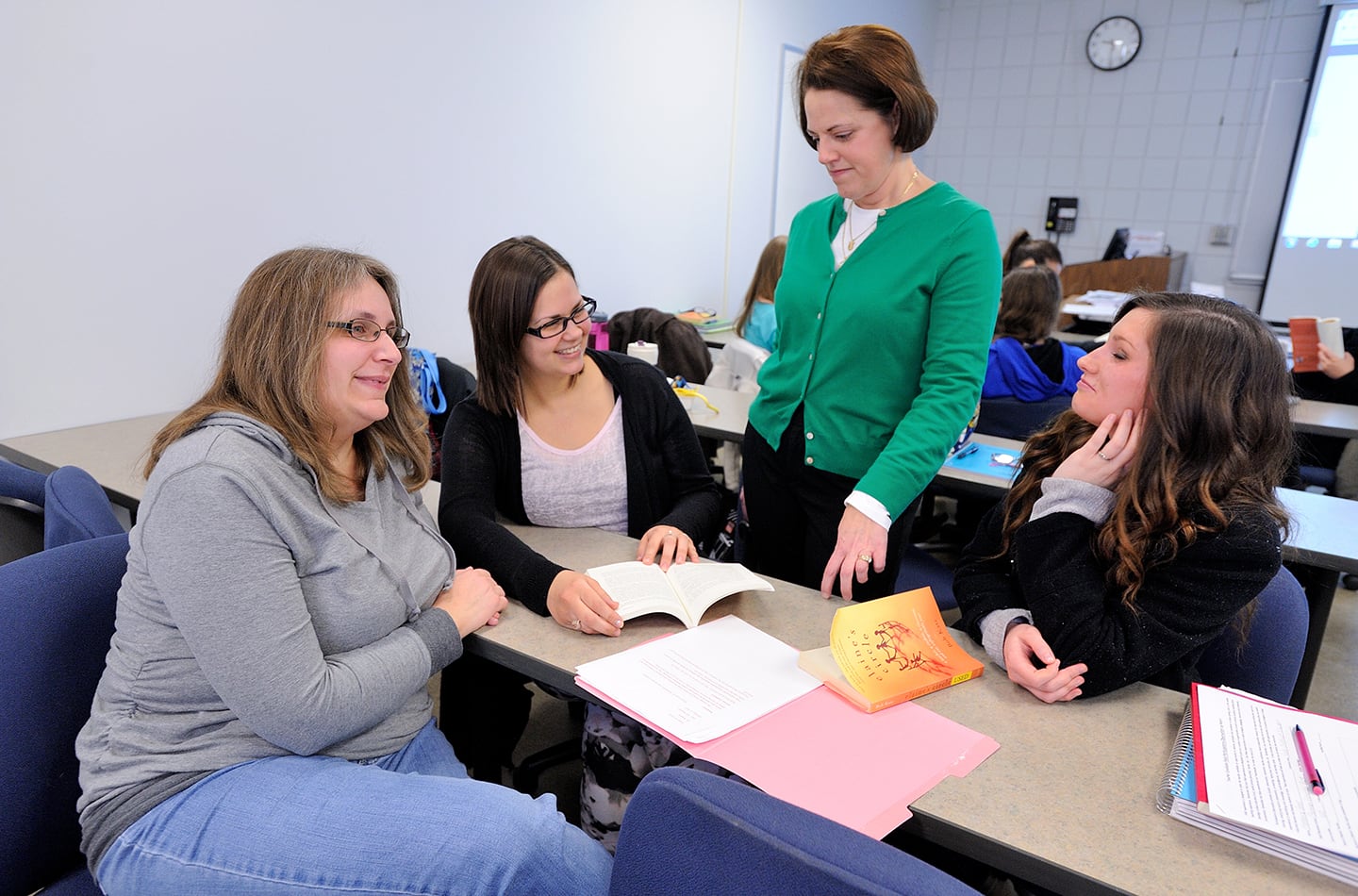 Three students receiving advice from an instructor in a classroom