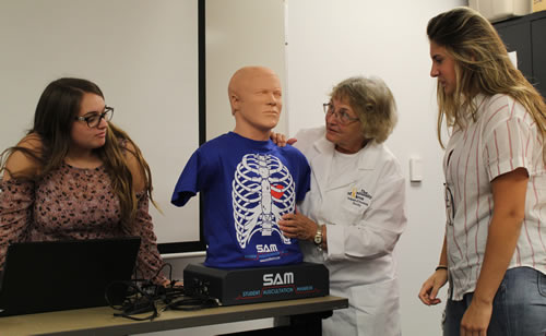 Marlene Huff, associate dean school of nursing (center), is explaining to  students (L/R) Ariel Snyder and Alexandra Huffman what they will be learning from the Student Auscultation Manikin.